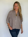 Brown gingham puff sleeve shirt with button front and split crew neckline worn by a woman.